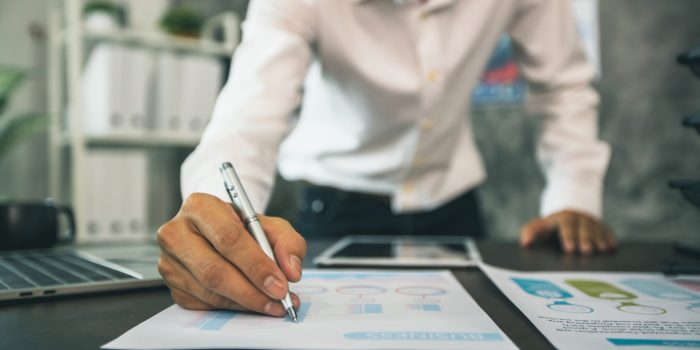 close up hand of business man check and planning on financial graph on table in office, strategy and work concept
